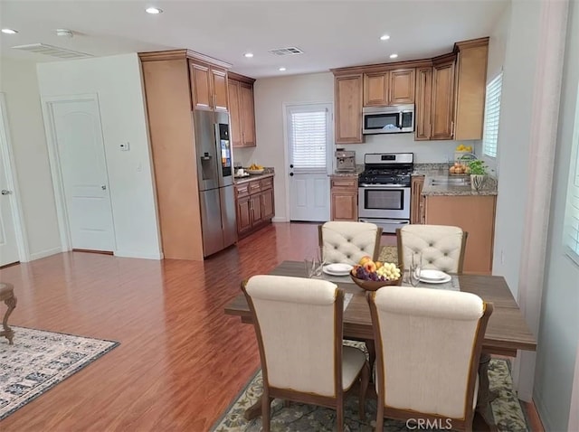 kitchen featuring appliances with stainless steel finishes, hardwood / wood-style flooring, and light stone counters