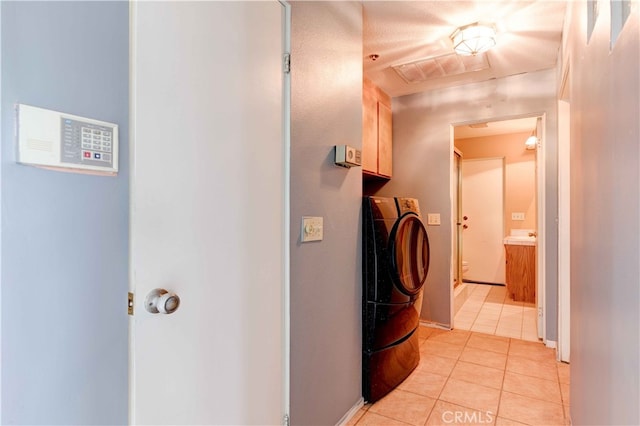 clothes washing area featuring cabinets, washer / clothes dryer, and light tile patterned floors