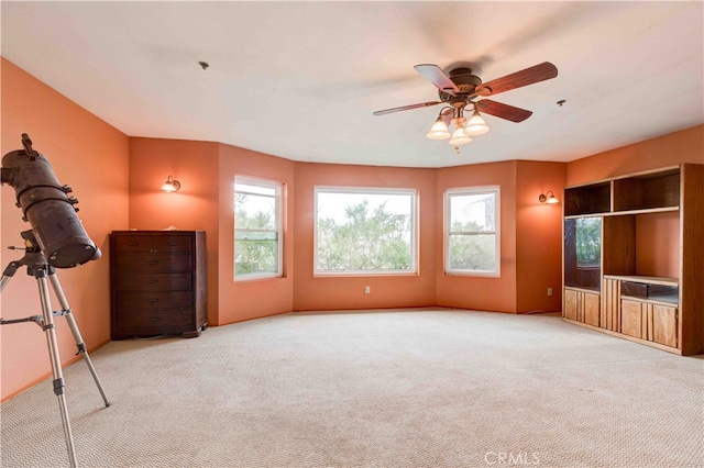 interior space with ceiling fan, light colored carpet, and a healthy amount of sunlight