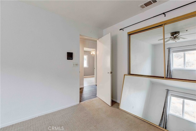 carpeted spare room with a wealth of natural light and ceiling fan