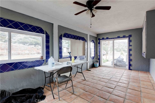 dining room featuring ceiling fan, a textured ceiling, and a healthy amount of sunlight