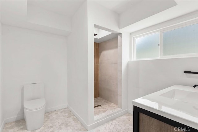 bathroom featuring a tile shower, vanity, and toilet