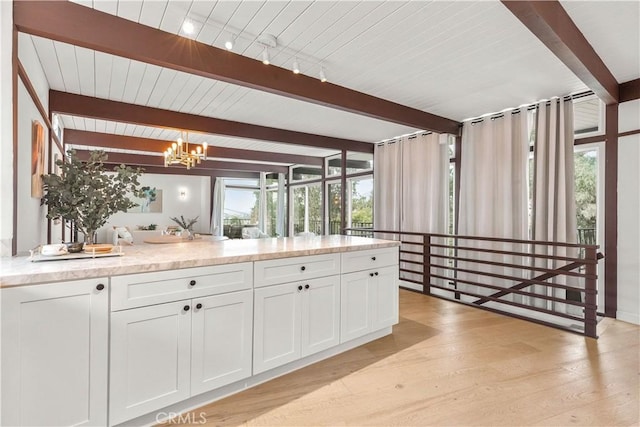 kitchen featuring beam ceiling, pendant lighting, white cabinetry, and light wood-type flooring