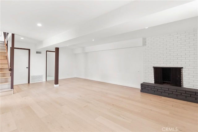 basement with a brick fireplace and light hardwood / wood-style floors