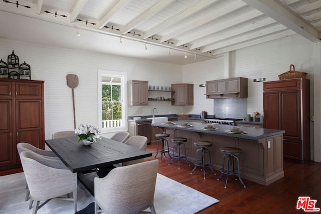 dining area featuring beam ceiling, dark hardwood / wood-style flooring, track lighting, and sink