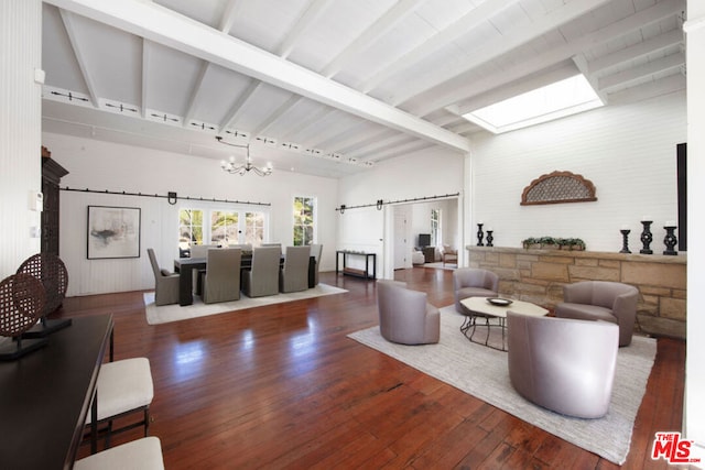 living room featuring beam ceiling, rail lighting, dark wood-type flooring, a barn door, and a chandelier