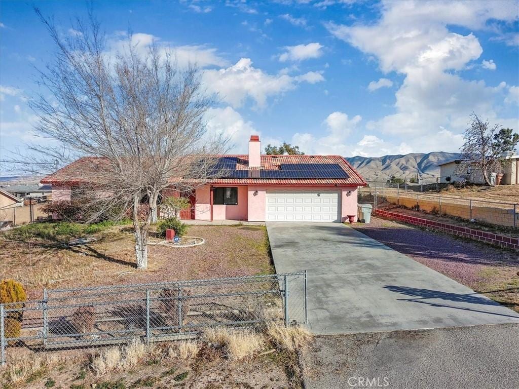 ranch-style house featuring solar panels, a garage, and a mountain view