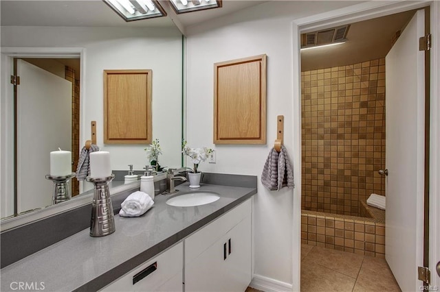 bathroom with vanity, tiled shower, and tile patterned flooring