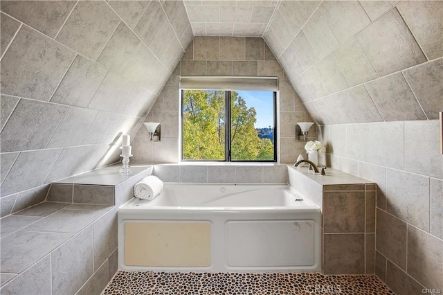 bathroom featuring a bathtub and lofted ceiling