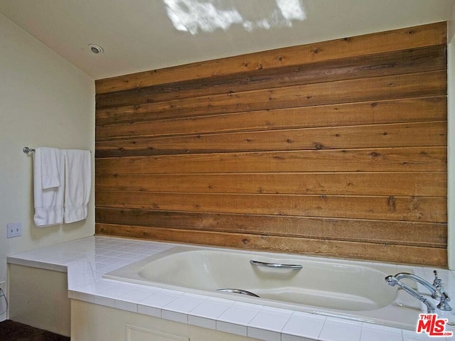 bathroom with lofted ceiling and tiled bath