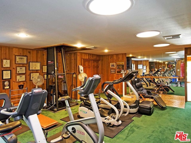 workout area with wood walls, a textured ceiling, and carpet flooring