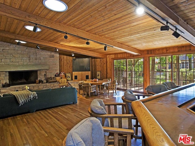 living room with wooden ceiling, wood walls, dark hardwood / wood-style floors, rail lighting, and a fireplace