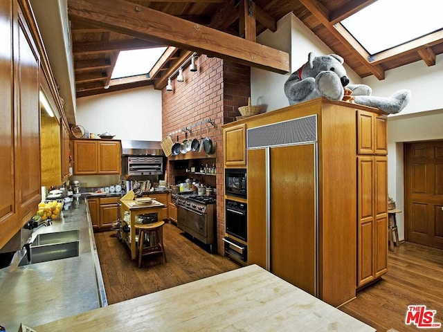 kitchen featuring a skylight, beamed ceiling, dark wood-type flooring, black appliances, and sink