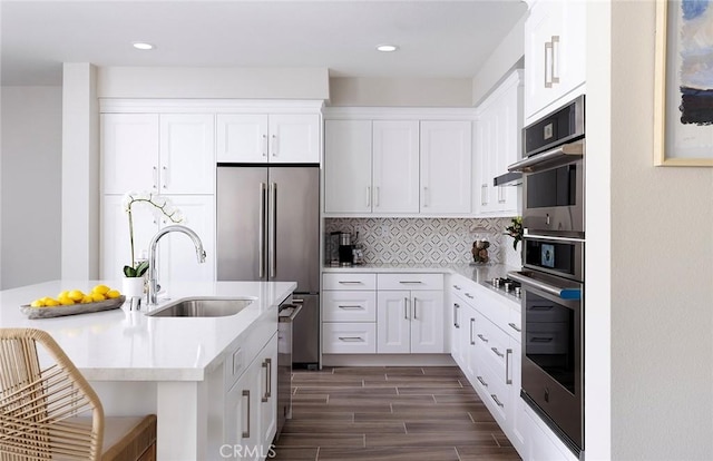 kitchen with stainless steel appliances, light countertops, decorative backsplash, wood tiled floor, and a sink