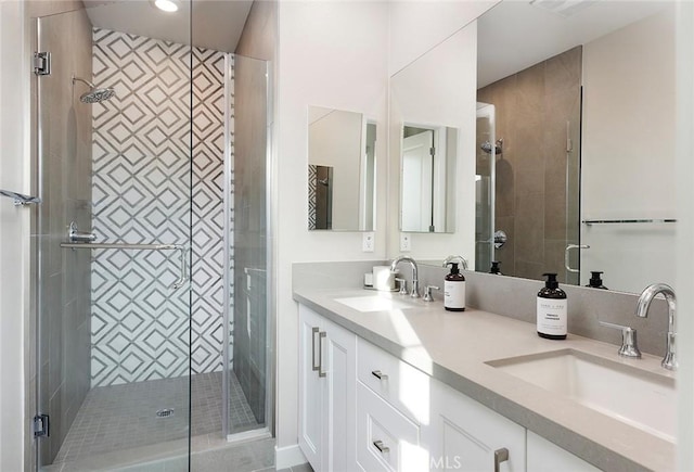 full bathroom with a sink, a shower stall, and double vanity