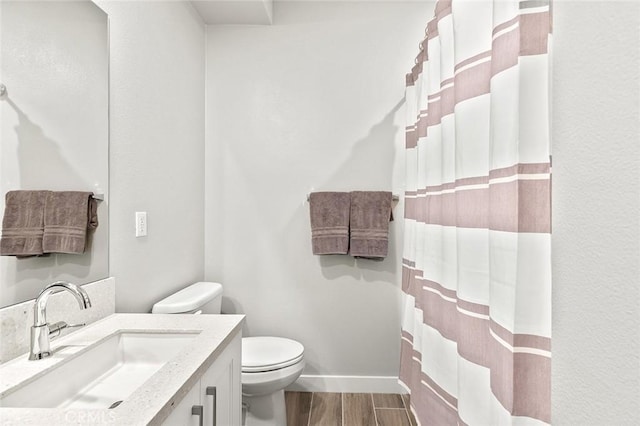 bathroom featuring curtained shower, toilet, wood finish floors, vanity, and baseboards