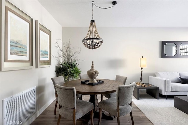 dining space featuring visible vents, light wood-style flooring, baseboards, and an inviting chandelier