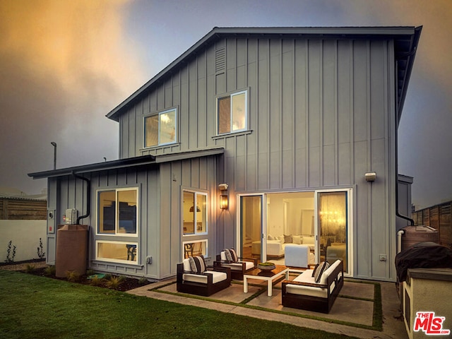 rear view of house with outdoor lounge area, a lawn, and a patio