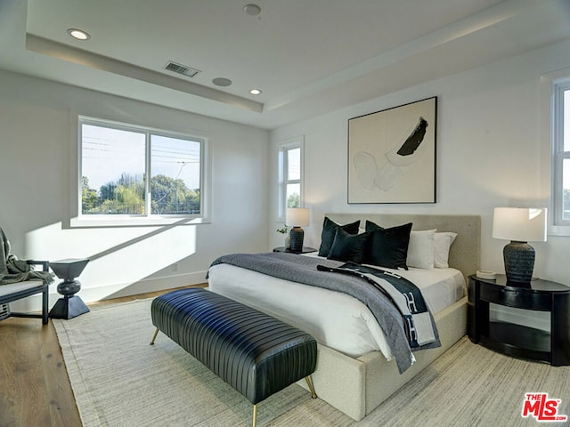 bedroom featuring a raised ceiling and light hardwood / wood-style floors