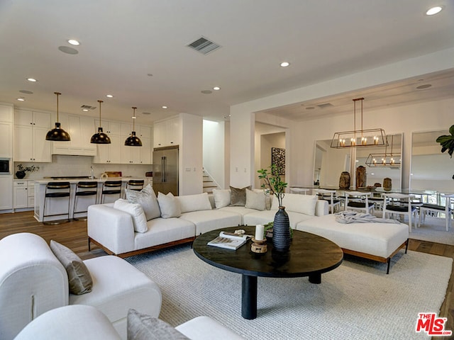 living room featuring an inviting chandelier, sink, and wood-type flooring