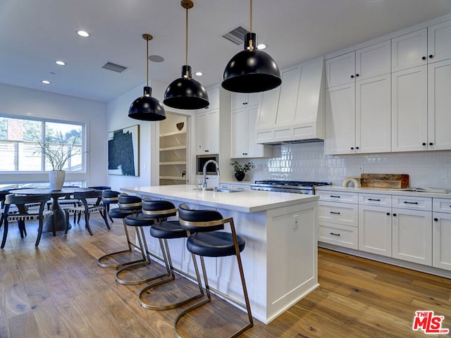 kitchen featuring white cabinets, custom range hood, and light hardwood / wood-style floors