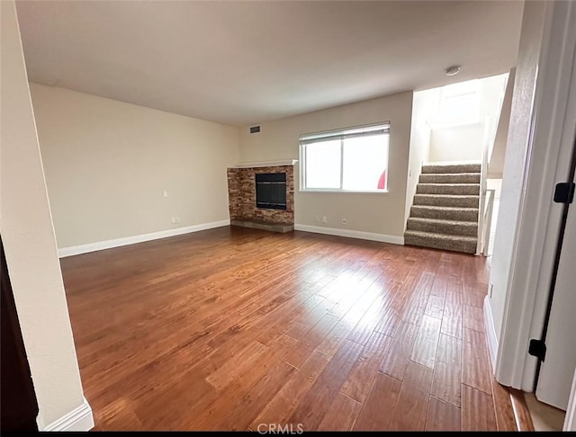 unfurnished living room featuring a stone fireplace and hardwood / wood-style flooring