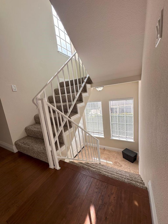 stairs featuring wood-type flooring and a textured ceiling