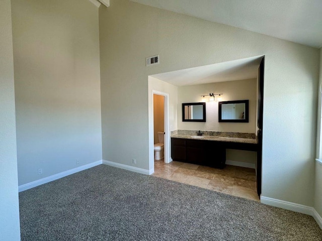 unfurnished bedroom with high vaulted ceiling, connected bathroom, sink, and light carpet