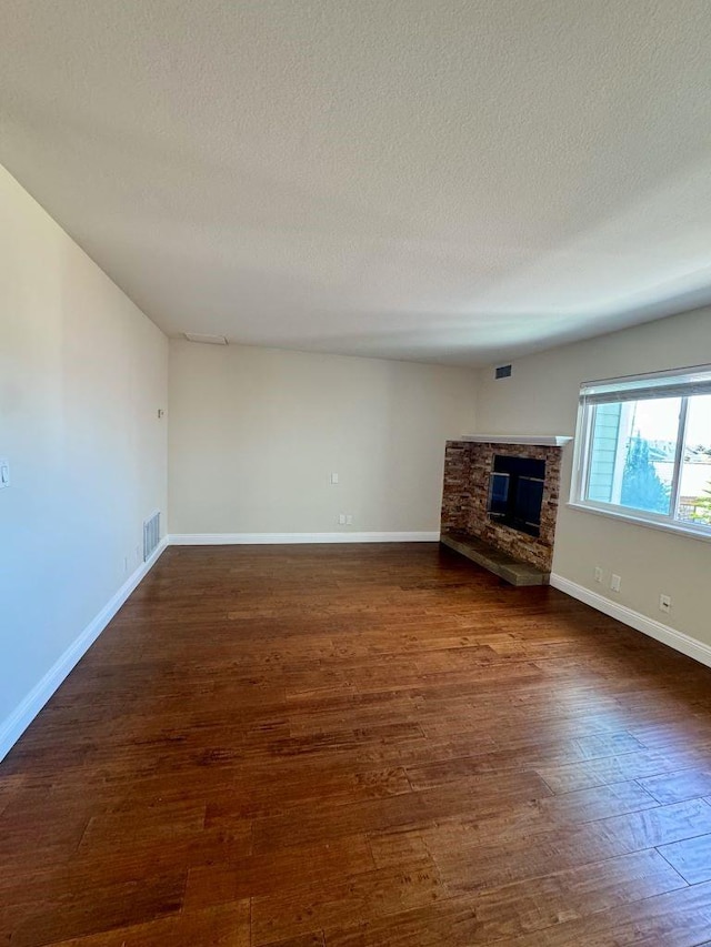 unfurnished living room featuring dark hardwood / wood-style floors, a textured ceiling, and a fireplace