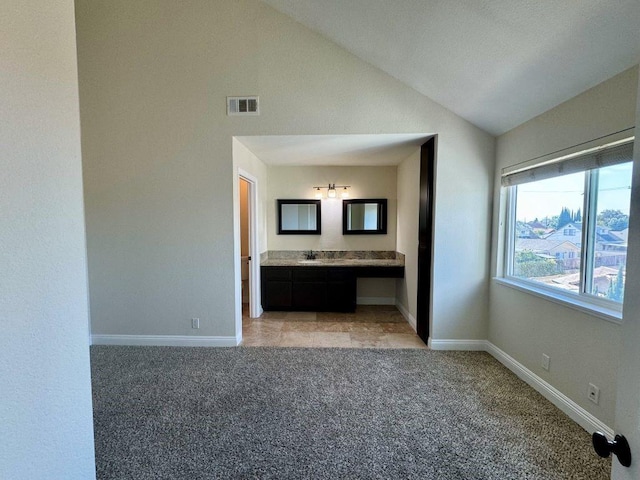 unfurnished bedroom featuring lofted ceiling, sink, light colored carpet, and connected bathroom