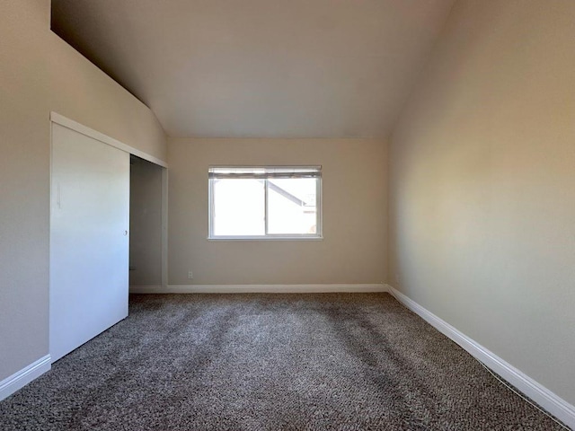 unfurnished bedroom featuring lofted ceiling, carpet floors, and a closet