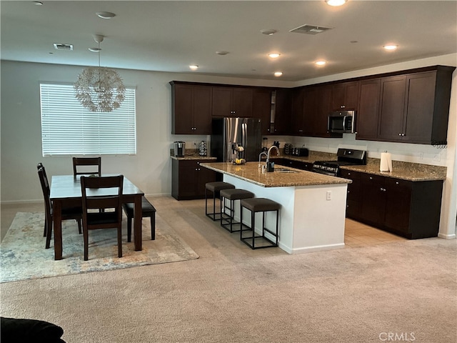 kitchen featuring light colored carpet, pendant lighting, a notable chandelier, stone countertops, and appliances with stainless steel finishes