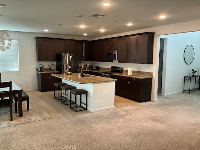 kitchen with stainless steel appliances, light colored carpet, sink, and stone countertops