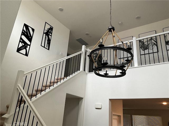 stairs with an inviting chandelier and a towering ceiling