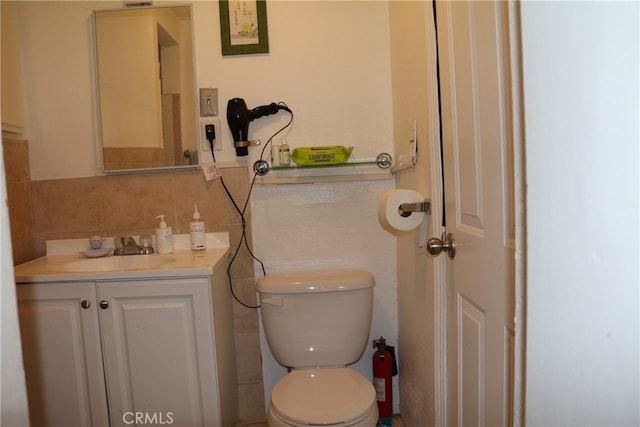 bathroom with tile walls, tasteful backsplash, toilet, and vanity