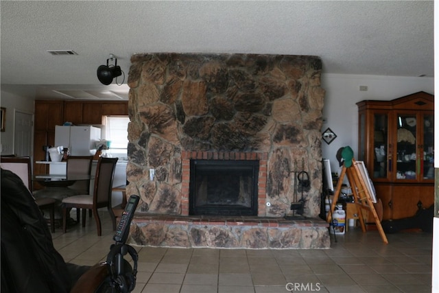 living room with a fireplace, light tile floors, and a textured ceiling