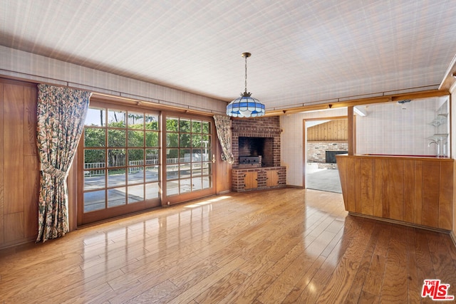 unfurnished living room with light hardwood / wood-style floors and a brick fireplace