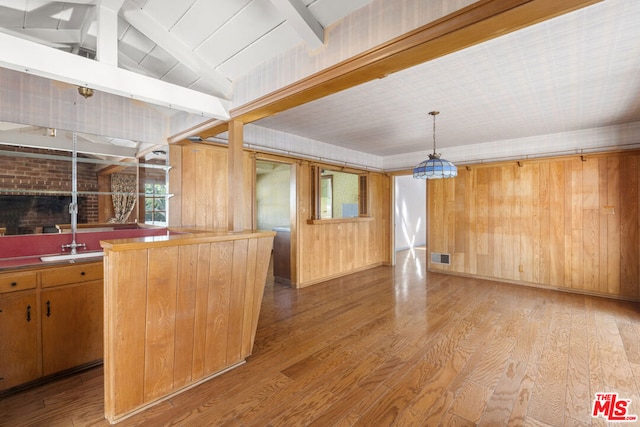 interior space featuring sink, decorative light fixtures, light hardwood / wood-style floors, and wood walls