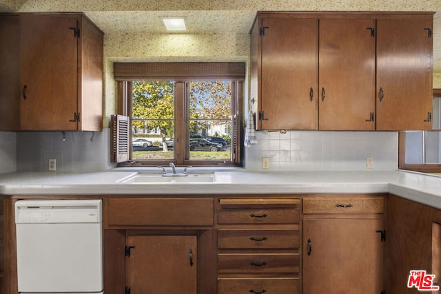 kitchen featuring white dishwasher, decorative backsplash, and sink