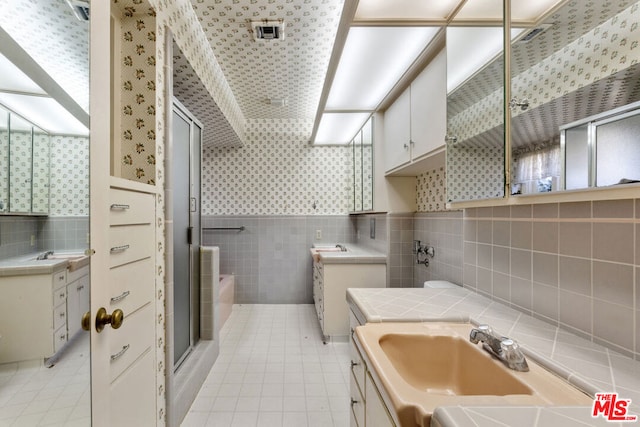 bathroom featuring tile patterned flooring, vanity, shower with separate bathtub, and tile walls