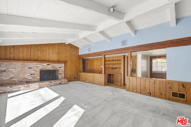 unfurnished living room featuring carpet, wood walls, beam ceiling, and a brick fireplace