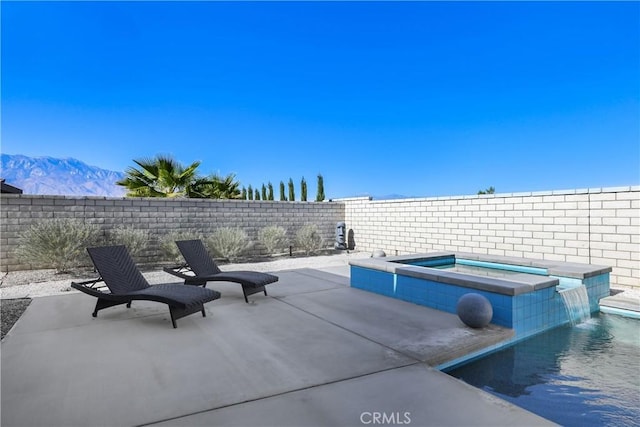 view of patio / terrace with a mountain view, a pool with hot tub, and pool water feature