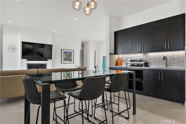 kitchen with a kitchen bar, tasteful backsplash, light tile patterned floors, sink, and decorative light fixtures