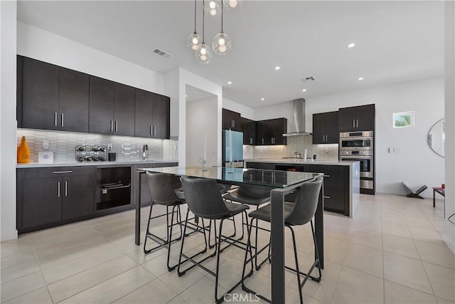 kitchen featuring stainless steel double oven, a center island, wall chimney exhaust hood, fridge, and light tile patterned floors