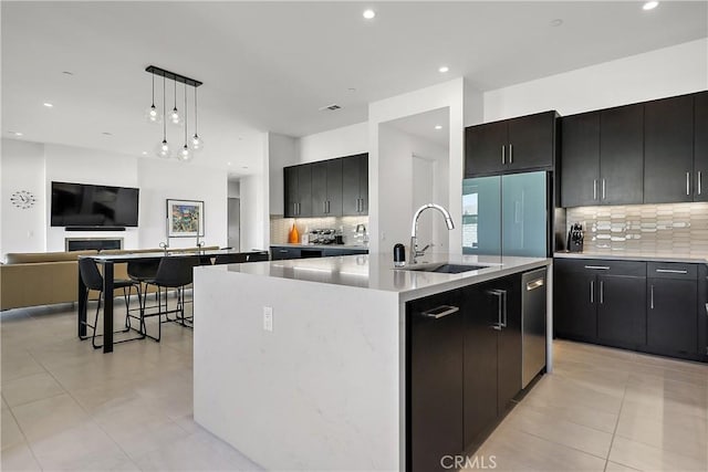 kitchen with pendant lighting, dishwasher, fridge, sink, and a kitchen island with sink