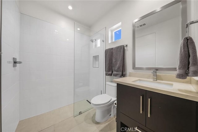 bathroom with vanity, toilet, tiled shower, and tile patterned flooring