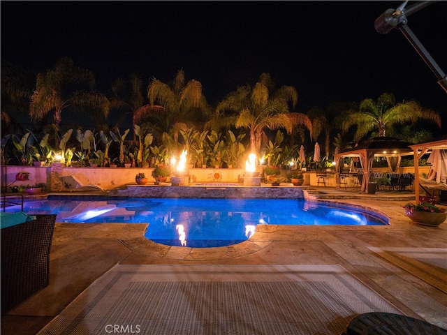 pool at twilight featuring a gazebo, a hot tub, and a patio area