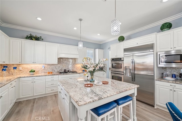 kitchen featuring built in appliances, decorative light fixtures, white cabinetry, and light hardwood / wood-style flooring