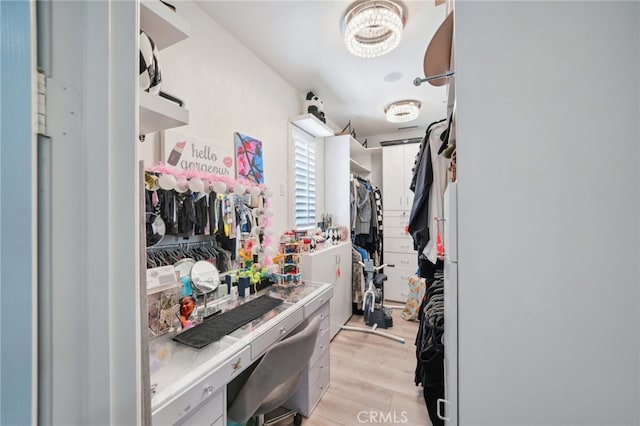 walk in closet with light wood-type flooring and a chandelier