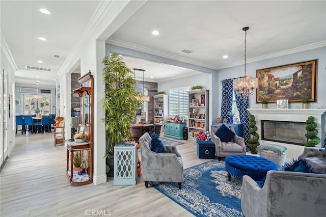 living room with ornamental molding, light wood-type flooring, and a chandelier